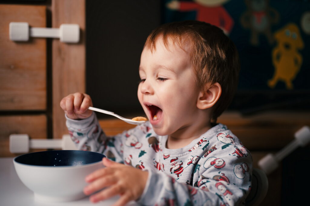 Toddler in Santa shirt sitting and eating